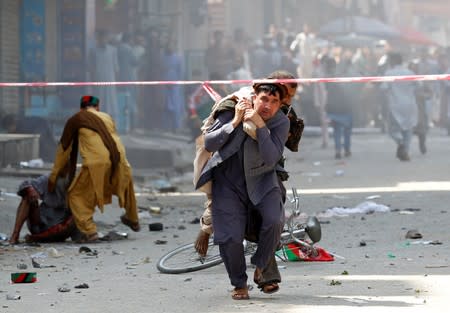 A man caries a wounded person to the hospital after a blast in Jalalabad