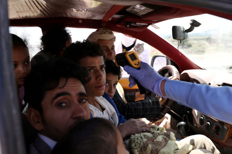 FILE PHOTO: A health worker takes the temperature of people riding a taxi van, amid concerns of the spread of the coronavirus disease (COVID-19), at the main entrance of Sanaa, Yemen