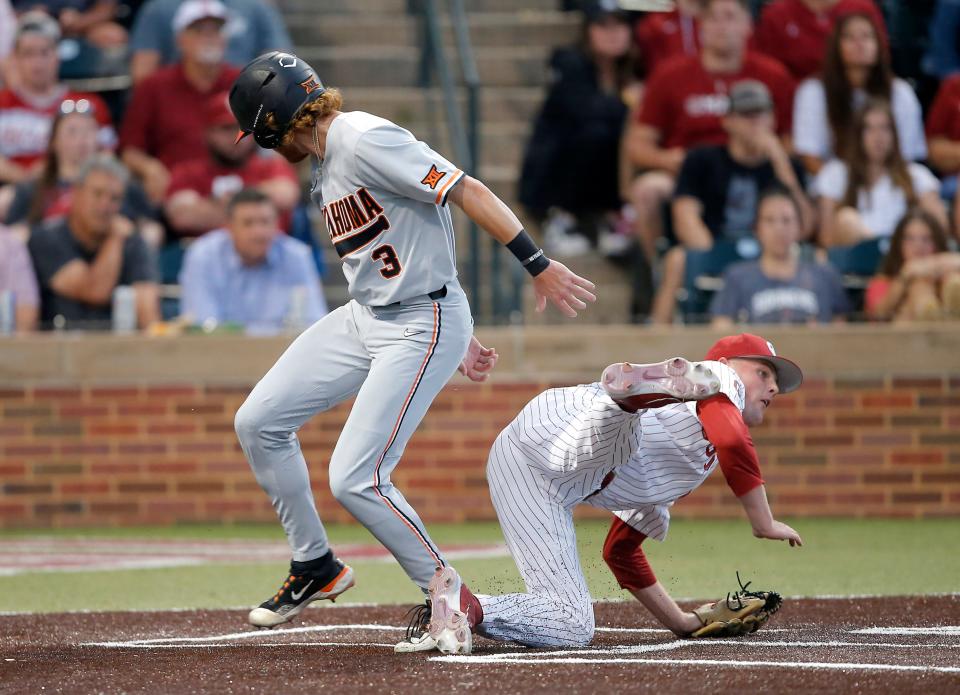 OSU's Carson Benge (3) scores on a passed ball as OU's Carson Atwood (34) misses the tag in the fourth inning Thursday night.