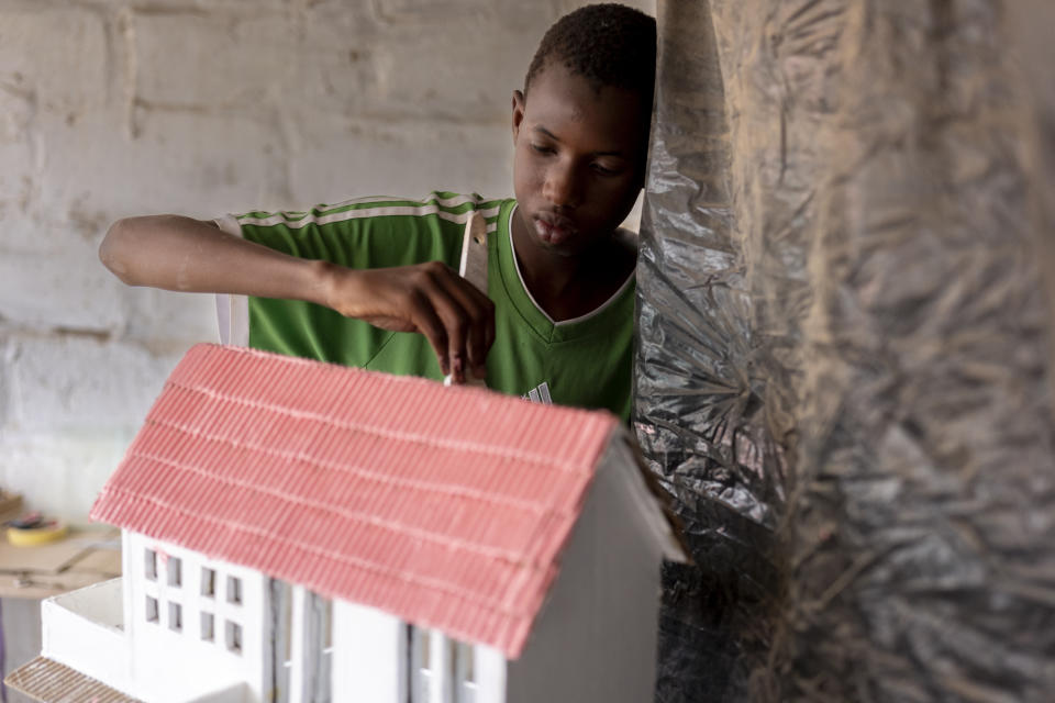 Mouhamed Sall, who is deaf, and known for his talent for drawing and manual activities, paints a small house he built in Pikine, Senegal, Monday, March 18, 2024. Sall and three other students are part of a new approach in a small number of schools in Senegal that seat those who are deaf and hard of hearing with the rest of the class. (AP Photo/Sylvain Cherkaoui)