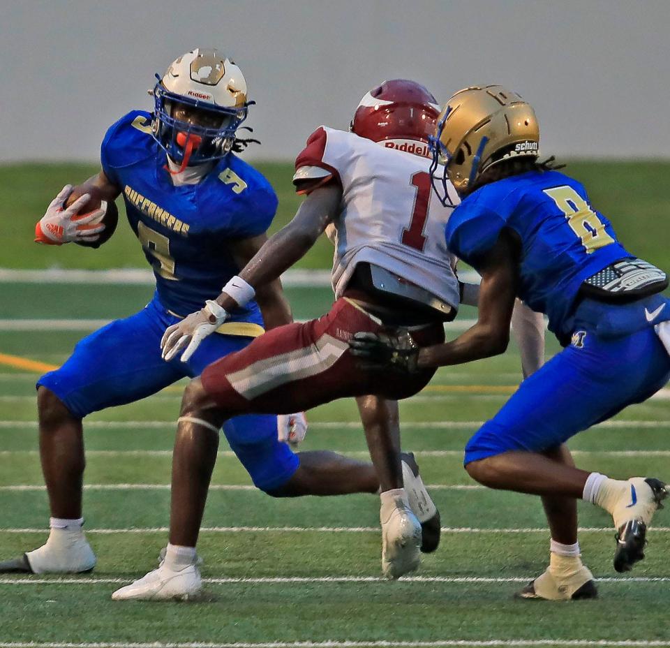 Mainland High School Player (9) Khamani Robinson runs pass a Raines player (1) Bishop Borger as Mainland player (8) Emmanuel Yisrael holds him off