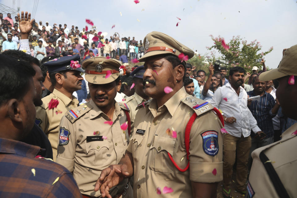 People throw flower petals on the Indian policemen guarding the area where rape accused were shot, in Shadnagar some 50 kilometers or 31 miles from Hyderabad, India, Friday, Dec. 6, 2019. An Indian police official says four men accused of raping and killing a woman in southern India have been fatally shot by police. (AP Photo/Mahesh Kumar A.)