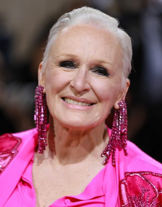 A closeup of Glenn Close smiling and wearing long earrings