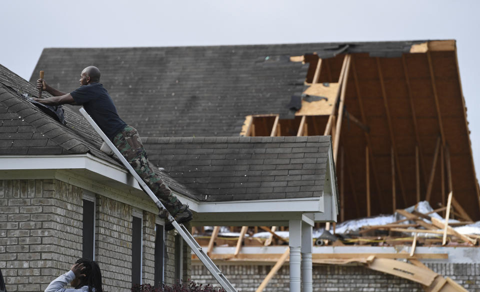 Alfred Lee covers a damaged spot on the roof of his home on Elvis Presley Drive in Tupelo, Miss., Monday, May 3, 2021. Multiple tornadoes were reported across Mississippi on Sunday, causing some damage but no immediate word of injuries.(AP Photo/Thomas Graning)
