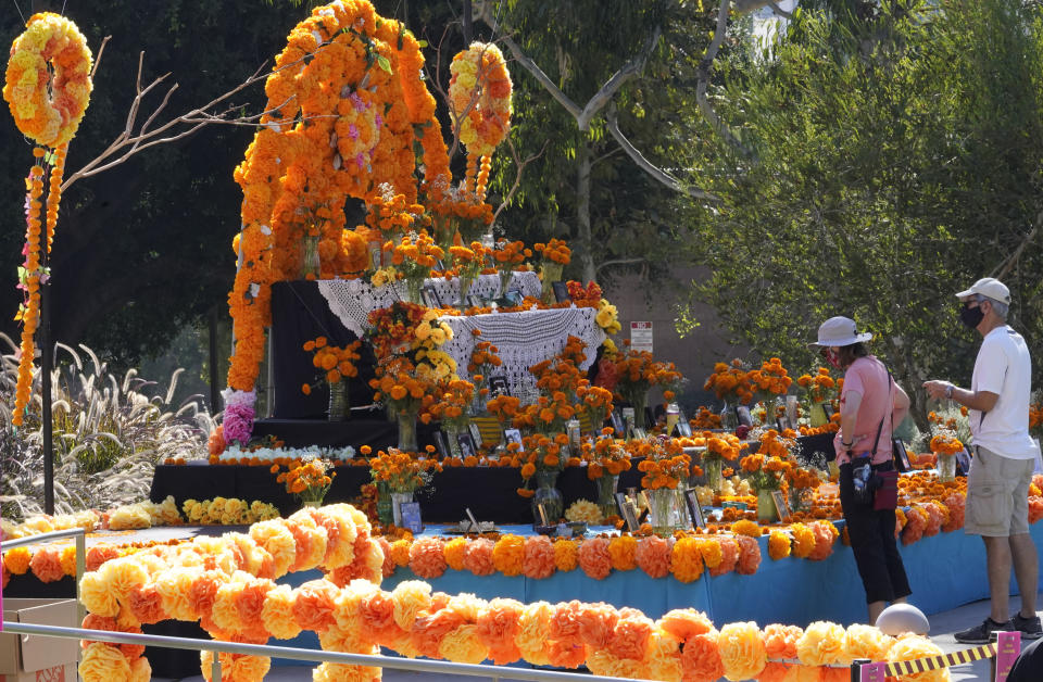 Unas personas observan una ofrenda colocada por la festividad del Día de los Muertos en Los Ángeles, el jueves 29 de octubre de 2020. (AP Foto/Damian Dovarganes)
