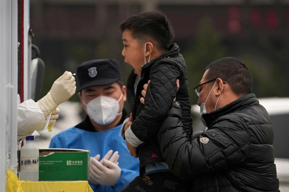 Seorang lelaki mengangkat anaknya untuk mendapatkan ujian COVID-19 di kemudahan ujian coronavirus mudah alih persendirian pada 29 Mac 2022, di Beijing.