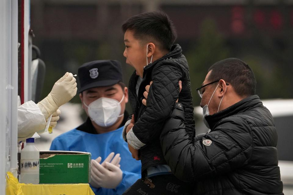 Een man tilt zijn kind op om op 19 maart 29 een COVID-2022-test te ondergaan in een particuliere mobiele testfaciliteit voor coronavirus in Peking.