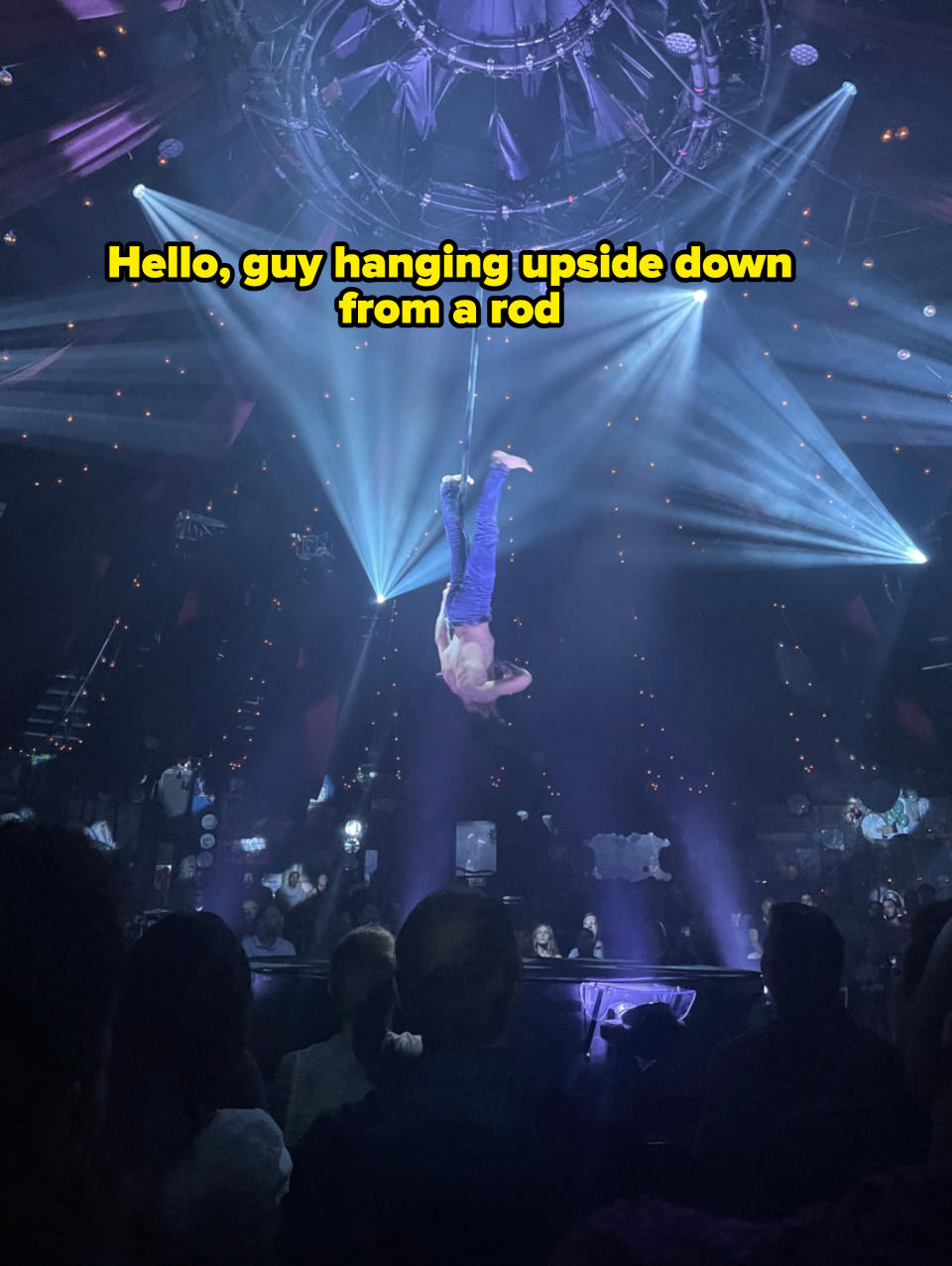 A guy from the Absinthe show hanging upside down from a rod