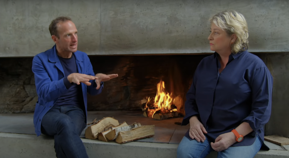 A man and woman speaking by a fireplace