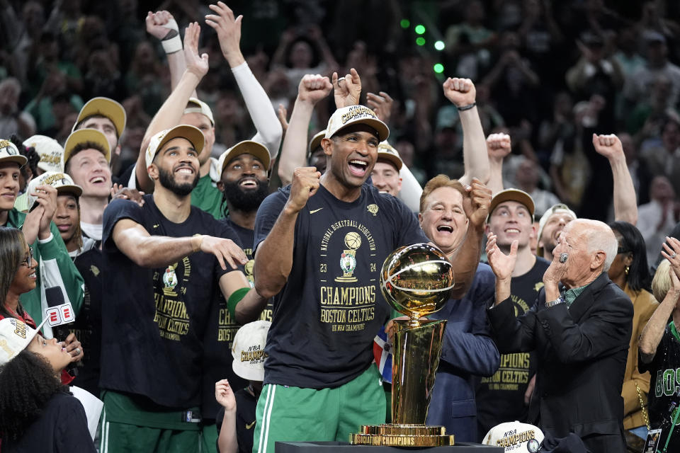 Boston Celtics center Al Horford and left center forward Jayson Tatum celebrate with their teammates near the Larry O'Brien Championship Trophy after winning the NBA championship with a Game 5 victory over the Dallas Mavericks on Monday, June 17, 2024, in Boston.  (AP Photo/Charles Krupa)