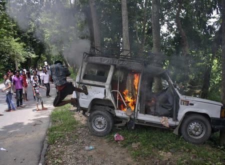 A demonstrator kicks a vehicle that was set on fire during a protest at Golaghat district in the northeastern Indian state of Assam August 20, 2014. REUTERS/Stringer