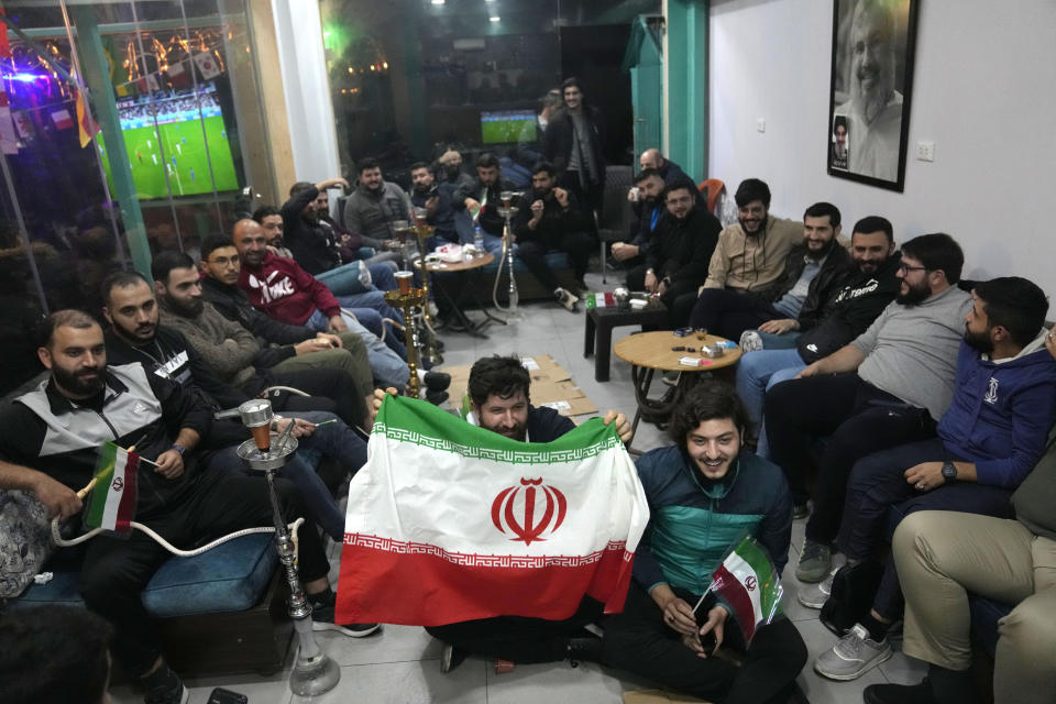 Lebanese fans of Iran's team sitting at a coffee shop smoke water pipes, as they watch the World Cup group B soccer match between Iran and the United States, in the Hezbollah stronghold in the southern suburbs of Beirut, Lebanon, Tuesday, Nov. 29, 2022. (AP Photo/Hussein Malla)