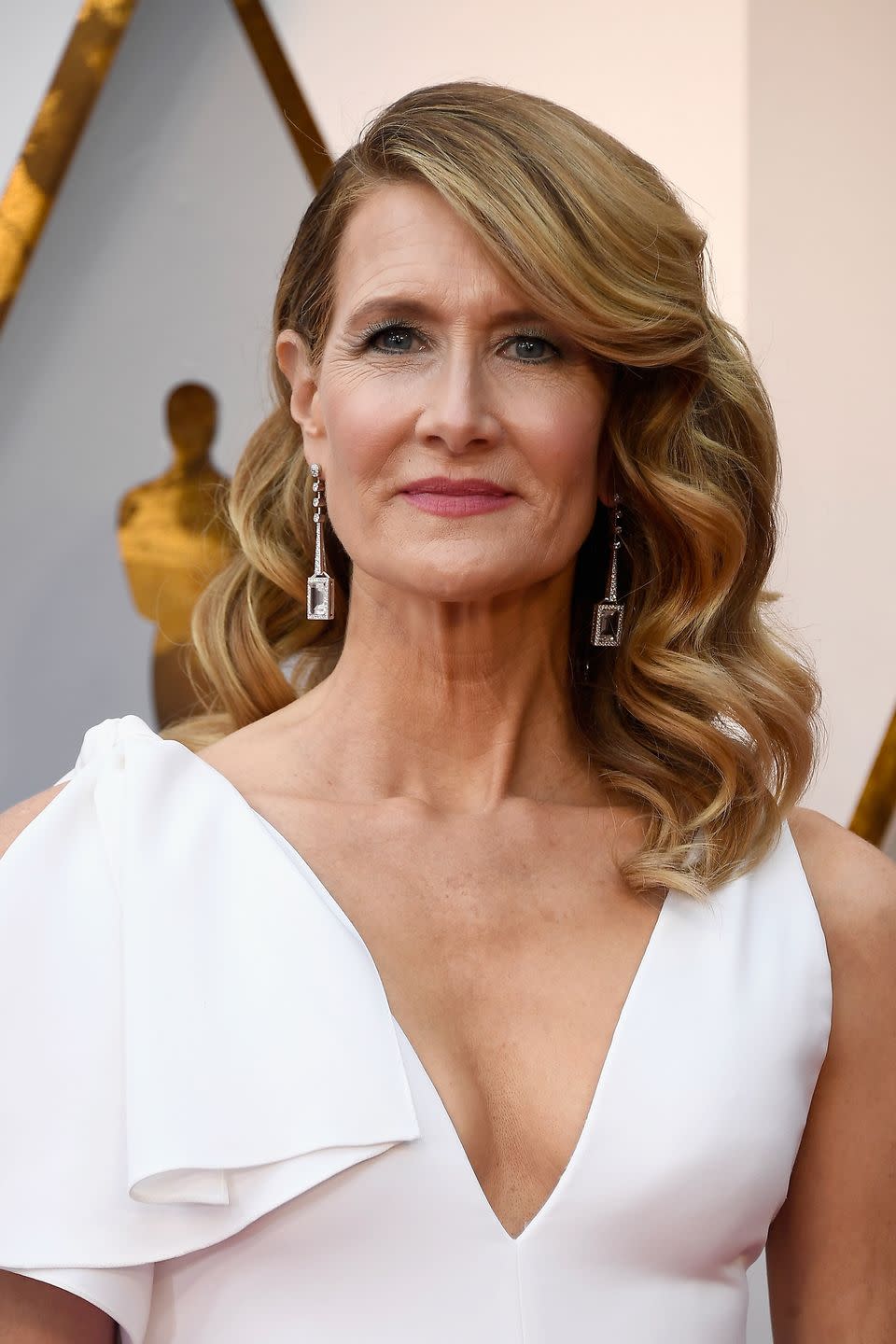 <p>If you've always wanted bangs but aren't <em>quite</em> ready to make the commitment to having them in your face all the time, try bangs that sweep off to one side. Style the rest of your hair asymmetrically and wavy for a beautiful Laura Dern-inspired look.</p>