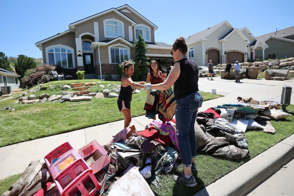 Kristin Hartness, Emily Hartness and Monett Rupp look at what is and isn’t salvageable after the Hartness’ home flooded in Draper on Friday, Aug. 4, 2023. Draper Mayor Troy Walker declared a state of emergency due to flooding. | Kristin Murphy, Deseret News