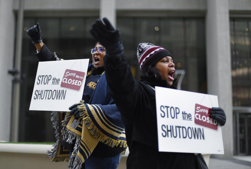 Two protesters hold signs reading: Sorry, we're closed; stop the shutdown.