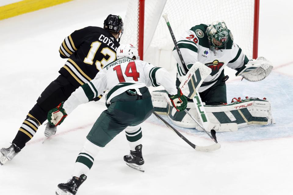 Minnesota Wild's Marc-Andre Fleury (29) blocks a shot by Boston Bruins' Charlie Coyle (13) as Joel Eriksson Ek (14) defends in overtime during an NHL hockey game, Tuesday, Dec. 19, 2023, in Boston. (AP Photo/Michael Dwyer)