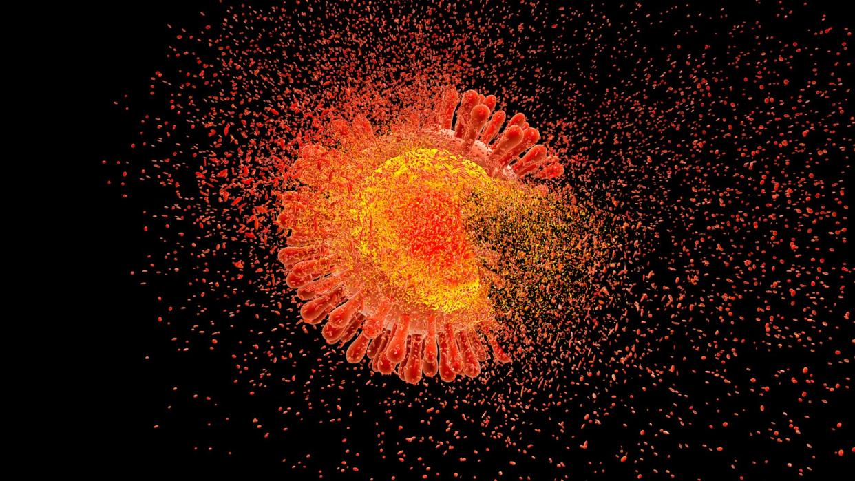  Illustration of a red and orange HIV virus disintegrating against a black background. 