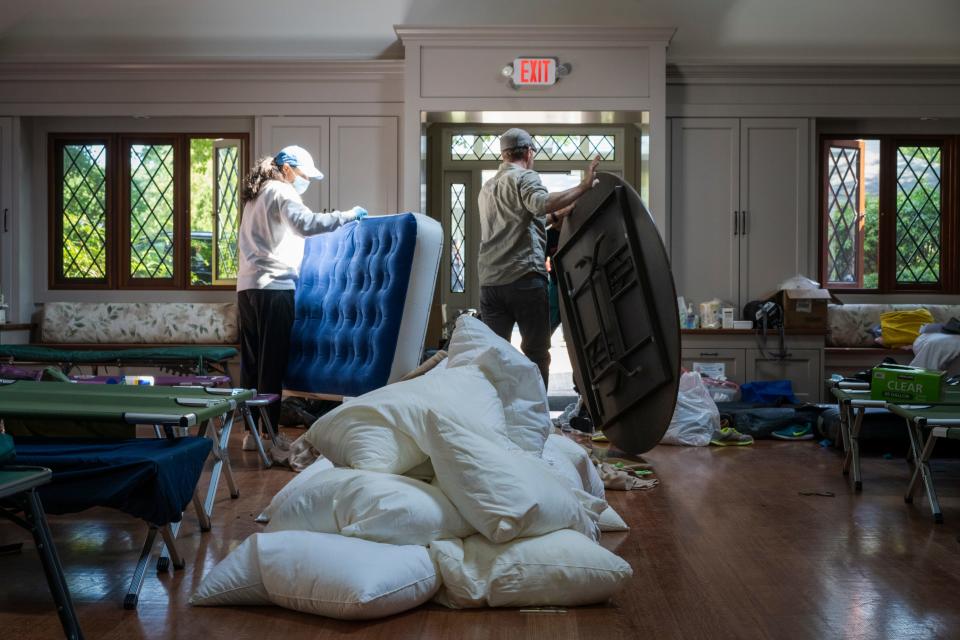 People are seen moving a mattress and a table out the door.