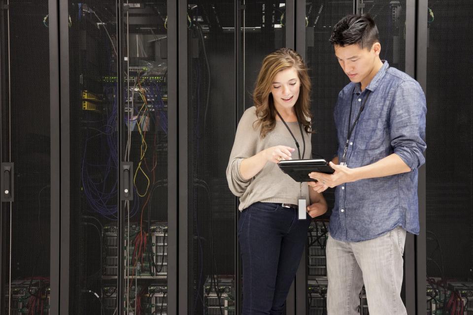 People look at a mobile device in front of stacks of supercomputers.