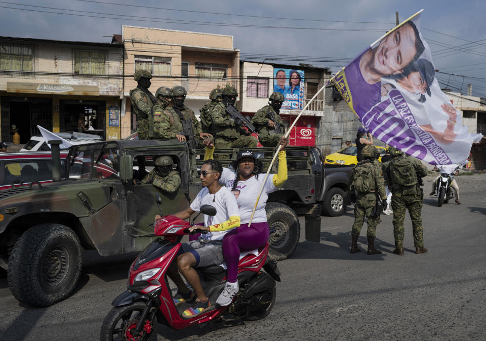 Soldados hacen guardia subidos en un vehículo militar al paso de simpatizantes del candidato presidencial Daniel Noboa, de la alianza política Acción Democrática Nacional, en un acto de campaña en el centro de Esmeraldas, Ecuador, el viernes 6 de octubre de 2023. La segunda vuelta electoral en Ecuador será el domingo 15 de octubre. (AP Foto/Rodrigo Abd)