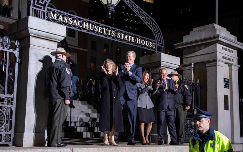 Gov. Charlie Baker pauses at the State House front gate during his "lone walk" out of office, accompanied by his wife Lauren (left), and Lt. Gov. Karyn Polito and her husband Steve Rodolakis (right).