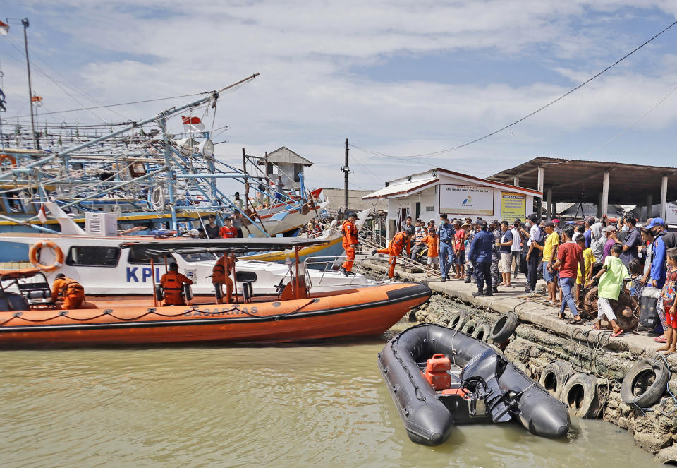 Residents look on as members of National Search and Rescue Agency (BASARNAS) prepare for a search mission for the victims of a ship collision, at a port in Indramayu, West java, Indonesia, Sunday, April 4, 2021. The collision between a cargo ship and a fishing boat left a number of people missing off Indonesia's main island of Java, officials said Sunday. (AP Photo/Panji Wisnu)