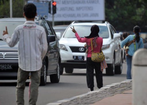 Nuraini (C), a traffic "jockey", gestures to passing motorists in Jakarta. Carpooling rules designed to ease Jakarta's notorious traffic jams have turned hitch-hiking into a stable but illegal profession for Indonesia's poor