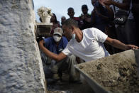 Alexsandro dos Santos seals with cement the niche that contains the remains of his 4-year-old daughter Emily Victoria Silva dos Santos, at a cemetery in Duque de Caxias, Rio de Janeiro state, Brazil, Saturday, Dec. 5, 2020. Grieving families held funerals for Emily and her 7-year-old cousin Rebeca Beatriz Rodrigues dos Santos, killed by bullets while playing outside their homes. Weeping and cries of “justice” were heard Saturday at their funerals, reflecting the families’ assertion that the children were killed by police bullets. (AP Photo/Silvia Izquierdo)