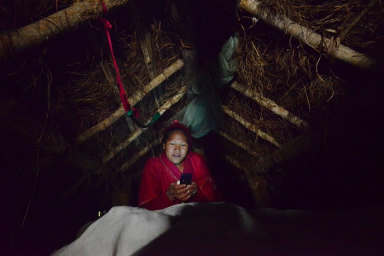 Nepalese woman Pabitra Giri checks her mobile phone inside a Chhaupadi hut during her menstruation period, in Surkhet District, some 520 km west of Kathmandu