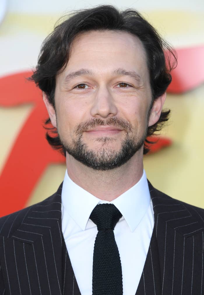 Joseph Gordon-Levitt smiling in a pinstriped suit and black tie