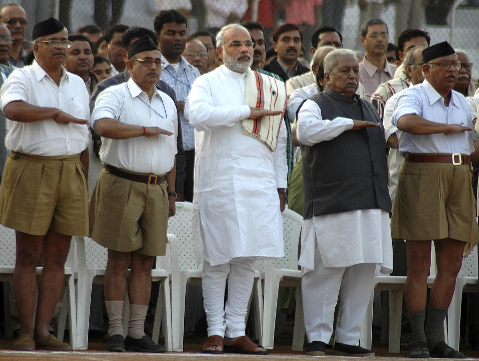 FILE- Gujarat state's then chief minister Narendra Modi, third left, former chief minister Keshubhai Patel, second right, and leaders of Hindu nationalist Rashtriya Swayamsevak Sangh (RSS), in front, salute during the concluding ceremony of the eight-day RSS convention in Ahmedabad, India, Jan. 1, 2006. Experts say Modi’s spiritual and political upbringing from the RSS is the driving force in everything he’s done as prime minister over the past 10 years. (AP Photo/Ajit Solanki, File)