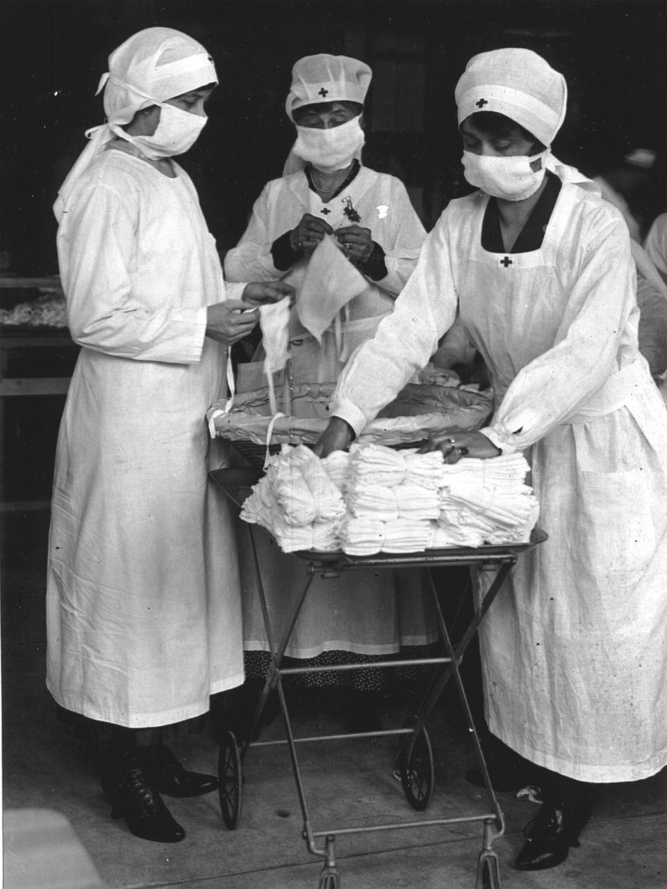 Red Cross workers of Boston, Massachussetts remove bundles of masks designated for American soldiers, while other nurses are busy making them, March 1919. (Photo by PhotoQuest/Getty Images)