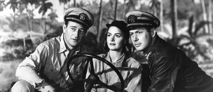 photo of a woman in the middle of a two men dressed in military uniforms in an open truck