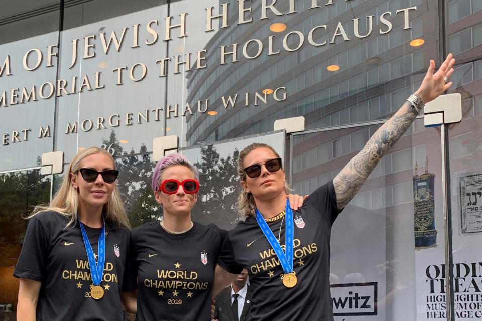 In this Wednesday, July 10, 2019 photo provided by Jeff Simmons, U.S. women's soccer player Ashlyn Harris raises her left arm next to her teammates, Allie Long and Megan Rapinoe, outside the Museum of Jewish Heritage before a victory parade in New York City, to celebrate the team's Women's World Cup title. On Friday, July 19, 2019, The Associated Press reported on stories circulating online incorrectly asserting that Harris is giving a Nazi salute. This photo was made after the museum hosted a breakfast for players before the ticker-tape parade, said Simmons, the executive vice president for Anat Gerstein, Inc., a public relations firm that works with the museum. (Jeff Simmons via AP)