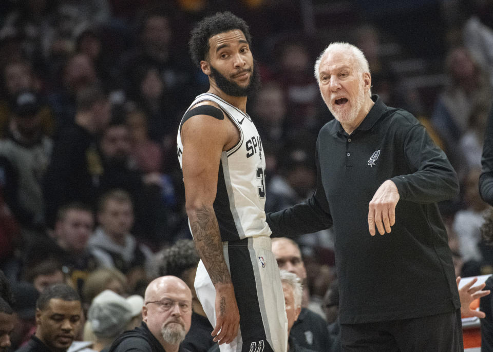 San Antonio Spurs head coach Greg Popovich, right, talks with Julian Champagnie, left, during the first half of an NBA basketball game against the Cleveland Cavaliers in Cleveland, Sunday, Jan. 7, 2024. (AP Photo/Phil Long)