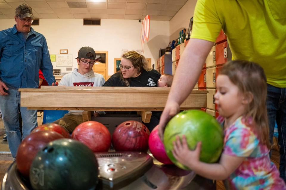 From left, Craig Herbst, of Manistique, looks over as his son Cole and daughter Taylor total their scores from a bowling game as Taylor's daughter Kynsleigh Schuetter and her father Brent Schuetter, both of Manistique, prepare to roll their ball down the lane at Ten Pin Alleys in Manistique on Sunday, March 24 ,2024.