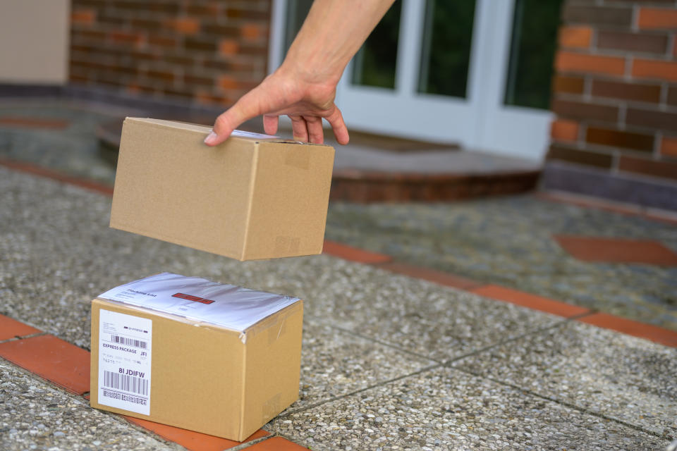 Close up of delivery man keeping cardboard packages at doorstep.