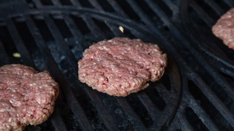 raw burgers on a grill