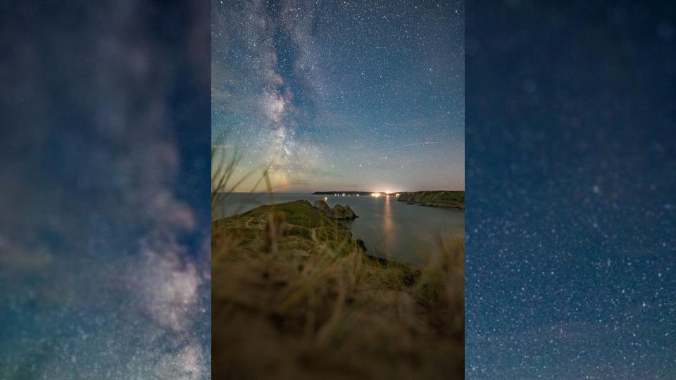 The milky way stretching up above the landscape at night