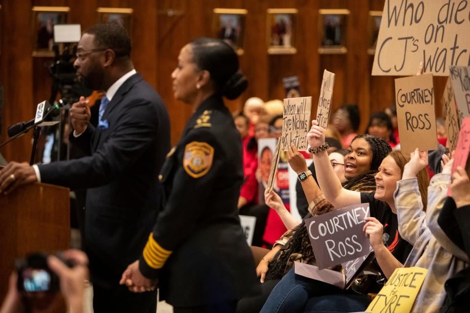 Protestors chant as Mayor Paul Young, with Police Chief Cerelyn “C.J.” Davis beside him, speaks to the city council after asking them to table indefinitely the reappointment of Davis at city hall on Tuesday, January 23, 2024.