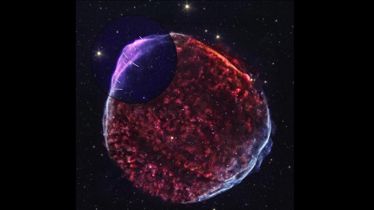  A blob-looking supernova with red and purple hues, set against a black background with stars. 