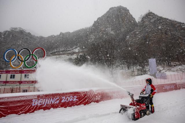 A worker clears snow off the women&#39;s downhill course as women&#39;s downhill training has been canceled due to snowfall during the 2022 Winter Olympic Games at the Yanqing National Alpine Skiing Centre in Yanqing on February 13, 2022. (DIMITAR DILKOFF/AFP via Getty Images)