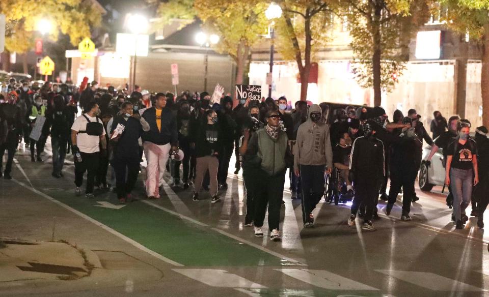 Protesters march in Wauwatosa, Wisconsin, past boarded up businesses on their way to  City Hall on Oct. 6, 2020. Earlier, District Attorney John Chisholm did not issue charges against Wauwatosa Police Officer Joseph Mensah in the the Feb. 2 fatal shooting of 17-year-old Alvin Cole at Mayfair Mall. Protests after the decision prompted  officials to shut down City Hall for about three days.