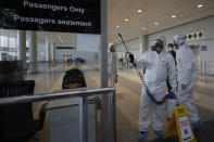 FILE - In this March 5, 2020 file photo, workers wearing protective gear spray disinfectant as a precaution against the coronavirus outbreak, in the departure terminal at the Rafik Hariri International Airport, in Beirut, Lebanon. On Wednesday, July 1, 2020, Beirut's airport is partially reopening after a three-month shutdown and Lebanon's cash-strapped government hopes thousands of Lebanese expatriates will return for the summer, injecting badly needed dollars into the sinking economy. (AP Photo/Hassan Ammar, File)