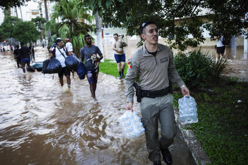 A military police carries water bottles for flood victims after heavy rains in Porto Alegre, Rio Grande do Sul state, Brazil, Monday, May 6, 2024. (AP Photo/Carlos Macedo)