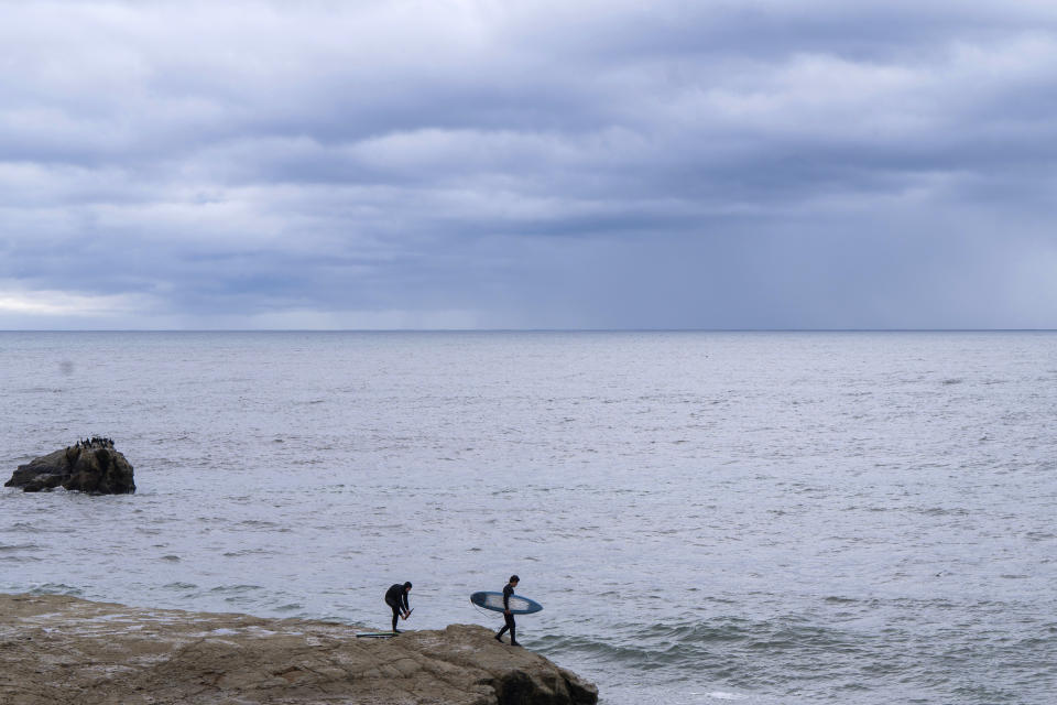 A surfer jumps in the water near Steamer Lane as storm clouds approach in Santa Cruz, Calif., Wednesday, Dec. 20, 2023. (AP Photo/Nic Coury)