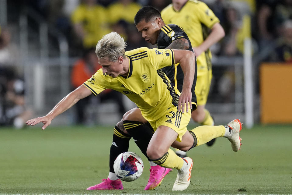 Nashville SC defender Lukas MacNaughton (3) falls to the turf as he battles Columbus Crew forward Cucho Hernández for the ball during the first half of an MLS soccer match Sunday, May 28, 2023, in Nashville, Tenn. (AP Photo/George Walker IV)