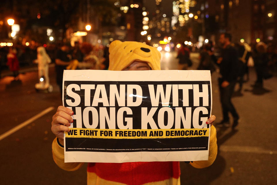 A reveler wears in costume holds up a political sign in support of Hong Kong during the 46th annual Village Halloween Parade in New York City. (Gordon Donovan/Yahoo News)
