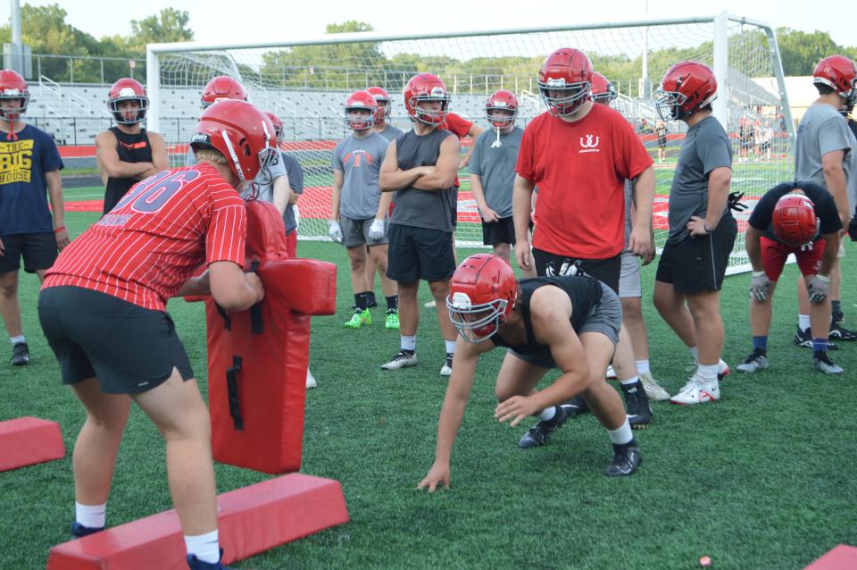 Sophomore Hudson Heams holds a blocking pad as senior Connor Green runs a drill during Bedford football practice.
