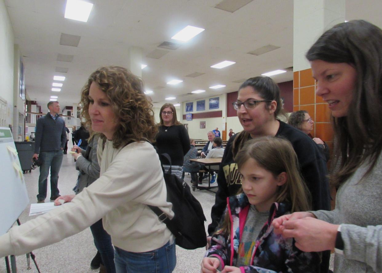 From left, Mindi Papania, Melanie Hyduke, Loraine Arch, 8, and Loraine's mother Janice study several boards which allowed residents to vote on various plans for the district.